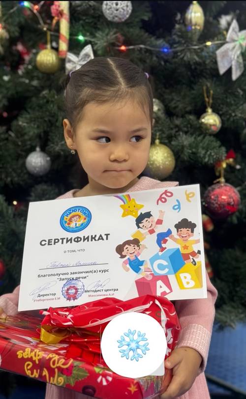 Девочка с сертификатом и подарком у новогодней ёлки